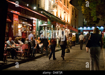 Les gens assis à l'extérieur des bars et des cafés de Montmartre - Paris en fin de soirée. Banque D'Images