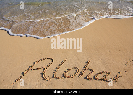 Aloha écrit dans le sable d'une plage hawaïenne Banque D'Images