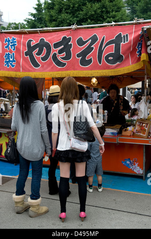 Deux jeunes femmes Japonais attendent en ligne dans le cadre d'un festival roten défends un yakisoba repas. Banque D'Images