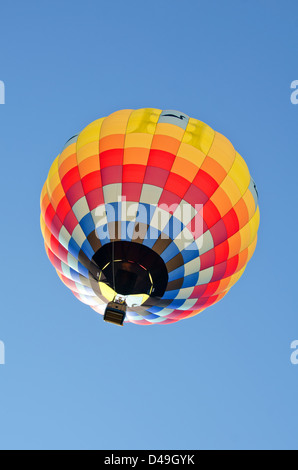 Aux couleurs vives, d'un ballon à air chaud s'élève dans un ciel bleu clair. Banque D'Images