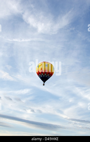Un ballon dirigeable monte à travers blanc wispy stratus dans un ciel bleu. Banque D'Images
