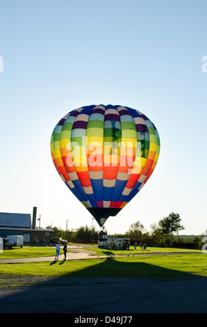 Le soleil qui s'allume les couleurs d'un ballon à air chaud et envoie un long voile sombre se répandre dans l'herbe. Banque D'Images