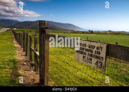 Une clôture et une salle, garder hors de signer le long de la route un à Big Sur, Californie, USA. Banque D'Images