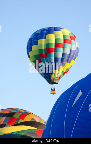 Aux couleurs vives, d'un ballon à air chaud s'élève dans un ciel bleu ciel du matin. Banque D'Images