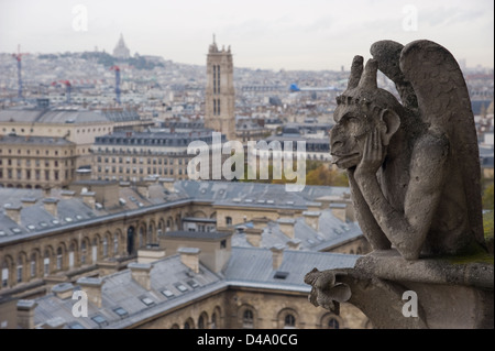 Gargouille en pierre (Chimera) surplombant la ville de Paris depuis la tour de la Cathédrale Notre Dame avec le Sacré-Cœur à l'arrière-plan Banque D'Images