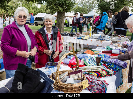 Deux dames âgées at a market stall fiers de leurs objets artisanaux pour la vente. Banque D'Images