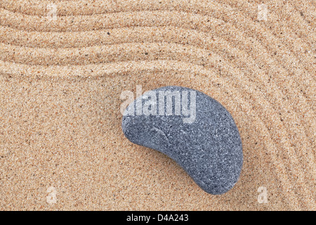 Un galet sur un jardin zen de sable ratissée Banque D'Images