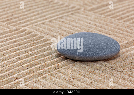 Un galet sur un jardin zen de sable ratissée avec patchwork patterns. Banque D'Images