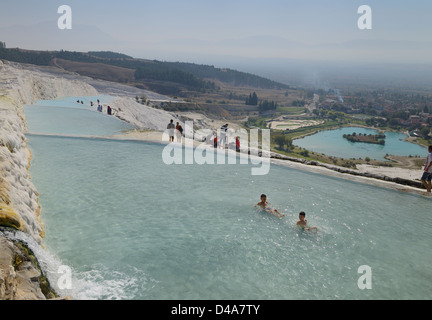 L'eau minérale qui se jettent dans des piscines thermales du dépôt de carbonate de calcium en travertin terrasses avec des touristes et baigneurs à Pamukkale Turquie Banque D'Images