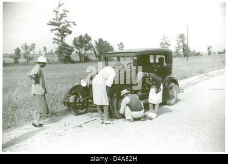 Une photographie de l'ère de la Grande dépression, représentant un homme afro-américain réparant un pneu sur une route près de la plantation de Knowlton, dans le Perthshire, en Écosse, mettant en évidence les défis des pannes d'automobiles. Banque D'Images