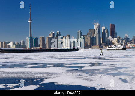 Femme marche sur le lac gelé de l'Ontario comme les quartiers island de retour à Toronto en hiver avec des toits de la ville Banque D'Images