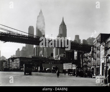 Cette photographie de Berenice Abbott de 1935 montre le front de mer de South Street à Manhattan, avec le pont de Brooklyn en arrière-plan. L'image met en valeur le paysage industriel et urbain de New York dans les années 1930 Banque D'Images