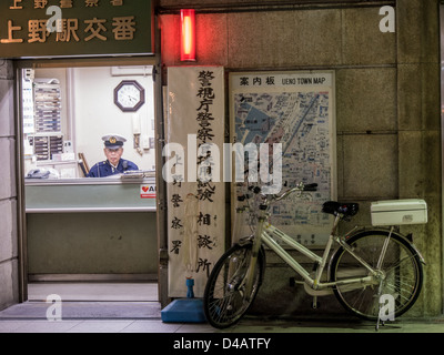 Un policier dans un Koban, un poste de police local, l'Onue, Tokyo, Japon. La police au Japon la bicyclette comme celle garée à l'extérieur. Banque D'Images