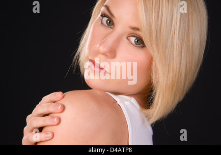 Un jeune et dynamique femme blonde regarde par-dessus son épaule dans la main tendue Headshot Banque D'Images