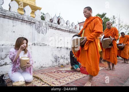 Luang Prabang, Laos. 11 mars 2013. Les moines bouddhistes, recueillir des aumônes pendant le tak bat à Luang Prabang. Le ''Tak Bat'' est un rituel quotidien dans la plupart des du Laos (et d'autres pays bouddhiste theravada comme la Thaïlande et le Cambodge). Moines quittent leurs temples à l'aube et marche silencieusement à travers les rues et les gens mettent du riz et autres produits alimentaires dans leurs bols d'aumône. Luang Prabang, dans le nord du Laos, est particulièrement bien connu pour le matin ''tak bat'' en raison du grand nombre de temples et de moines dans la ville Crédit : ZUMA Press, Inc. / Alamy Live News Banque D'Images