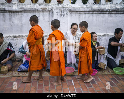 Luang Prabang, Laos. 11 mars 2013. Les moines novices bouddhistes de collecter des aliments au cours de l'tak bat. Le ''Tak Bat'' est un rituel quotidien dans la plupart des du Laos (et d'autres pays bouddhiste theravada comme la Thaïlande et le Cambodge). Moines quittent leurs temples à l'aube et marche silencieusement à travers les rues et les gens mettent du riz et autres produits alimentaires dans leurs bols d'aumône. Luang Prabang, dans le nord du Laos, est particulièrement bien connu pour le matin ''tak bat'' en raison du grand nombre de temples et de moines dans la ville Crédit : ZUMA Press, Inc. / Alamy Live News Banque D'Images