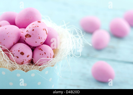 Oeufs de Pâques en rose un petit gâteau tasse sur fond de bois vintage bleu clair Banque D'Images