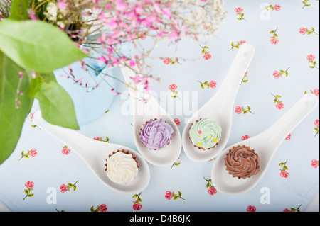 Quatre candy sur cuillère spécial avec une serviette sur la table, à côté d'un bouquet de fleurs Banque D'Images