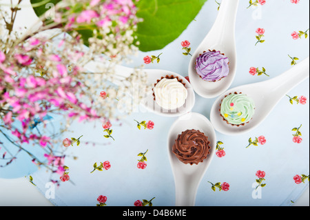 Quatre candy sur cuillère spécial avec une serviette sur la table, à côté d'un bouquet de fleurs Banque D'Images