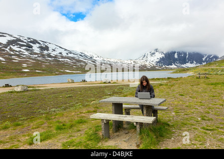 Jeune fille travaillant sur un ordinateur portable entre les montagnes, la Norvège Banque D'Images