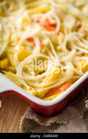 Close-up de pommes de terre au four au four avec l'oignon servi dans la cocotte blanche Banque D'Images