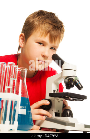 Cute boy dans le laboratoire à l'intermédiaire de microscope avec tubes à essai autour de Banque D'Images