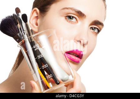Portrait of attractive woman holding glass lab avec instruments de maquillage Banque D'Images