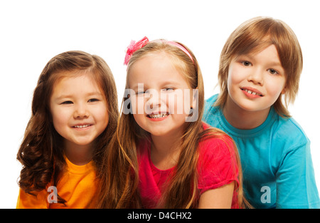 Libre d'un groupe de trois enfants, deux filles et garçon ensemble, la diversité à la heureux, riant, s'étreindre, assis sur le plancher isolé sur blanc Banque D'Images