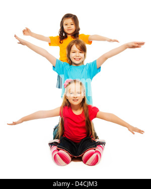 Trois enfants de la diversité à s'asseoir sur le sol les mains levée de suite une sur l'autre dans une ligne verticale, souriant, heureux, souriant, isolated on white Banque D'Images