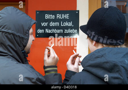 Deux fumeurs fument une cigarette à l'extérieur d'un pub qui conseille 'Veuillez être tranquille en dehors de la pub pour les voisins du ciel" à Munich, Allemagne, 15 janvier 2008. Une stricte interdiction de fumer dans toute l'Allemagne produit des clubs de fumeurs qui sont explicitement pour les fumeurs. Photo : Felix Hoerhager Banque D'Images