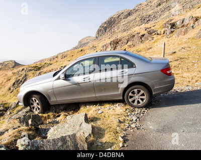 Une Mercedes qui a raté une hiarpin bend sur Hardknott Pass et s'écrasa sur les rochers et était sur le bord d'équilibrage Banque D'Images