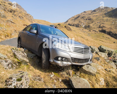 Une Mercedes qui a raté une hiarpin bend sur Hardknott Pass et s'écrasa sur les rochers et était sur le bord d'équilibrage Banque D'Images