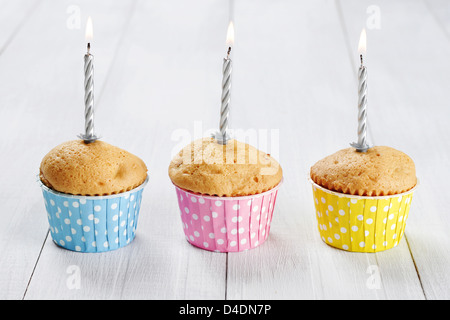 Trois muffins avec des bougies colorées en cas muffins on white background Banque D'Images