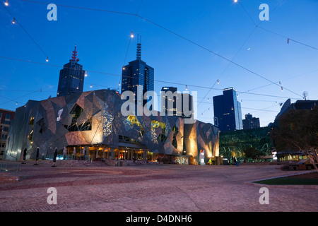 Federation Square allumé au crépuscule avec ville en arrière-plan. Melbourne, Victoria, Australie Banque D'Images