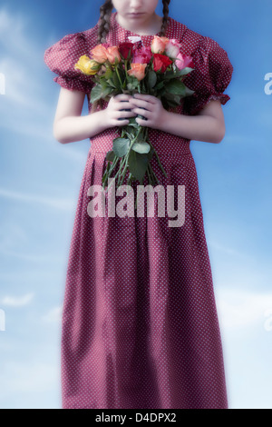 Une fille dans une robe rouge tenant un bouquet de fleurs Banque D'Images