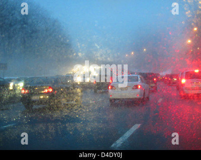 Le trafic sur une route humide des pluies au crépuscule Banque D'Images