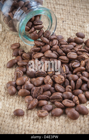 Les grains de café renversé sur petit pot de verre Banque D'Images