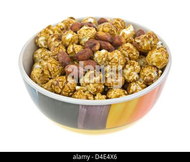 Un bol décoratif rempli de pop-corn caramel et arachides rôties couché sur un fond blanc. Banque D'Images