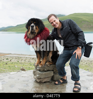 Homme posant avec un chien Saint Bernard sur les rives du lac sacré ; Shannan, Xizang, Chine Banque D'Images