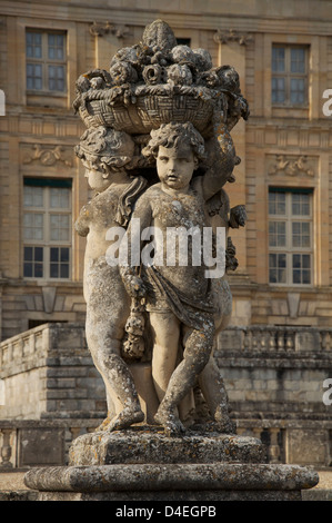 Une statue de chérubin nourrissons tenant une corbeille de fleurs et fruits, dans les jardins de l'époque baroque Le Château de Vaux-le-Vicomte. La France. Banque D'Images