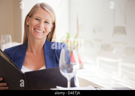 Smiling woman reading menu in restaurant Banque D'Images