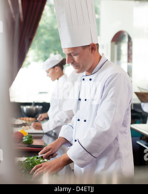 Chef chopping vegetables in restaurant kitchen Banque D'Images