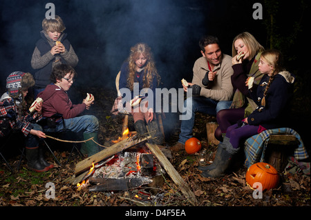 Manger en famille autour de feu de camp la nuit Banque D'Images