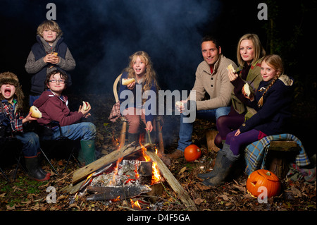 Manger en famille autour de feu de camp la nuit Banque D'Images