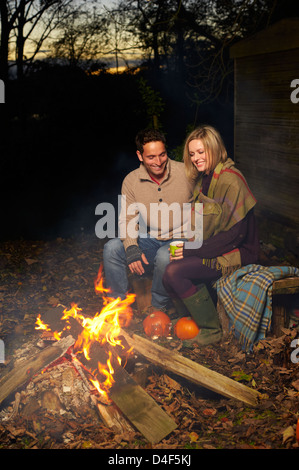 Couple talking autour de feu de camp la nuit Banque D'Images