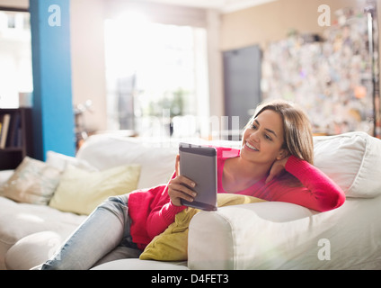 Woman using digital tablet on sofa Banque D'Images