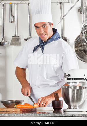 Young male Chef Cutting Carrots Banque D'Images