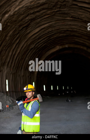 Worker holding sledgehammer dans tunnel Banque D'Images