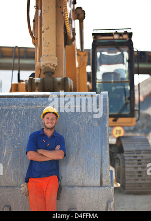 Worker standing by digger sur place Banque D'Images