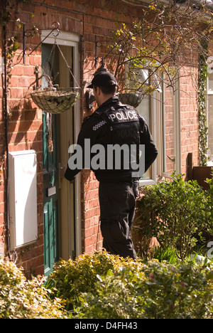 Agent de police entrant chambre de suspect qui a été arrêté pour menaces de mort, à selborne, Hampshire, Royaume-Uni. Banque D'Images